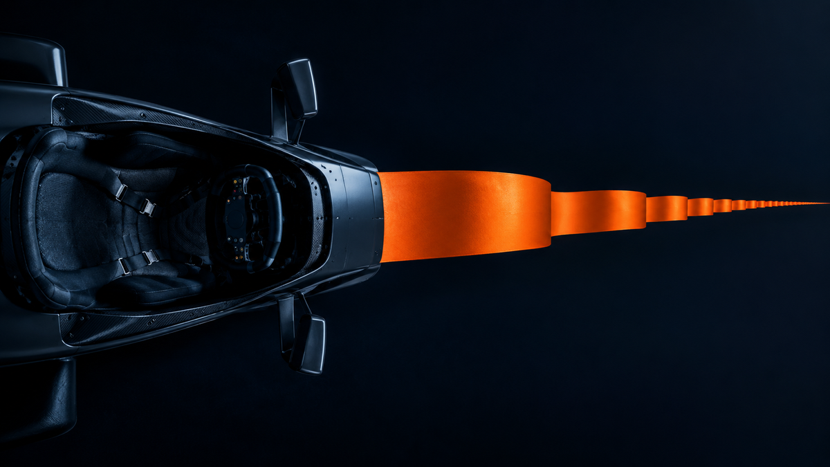 An empty Formula 1 cockpit seat and steering wheel seen from directly above in cool blue light, with a long orange band extending from the nose of the car far into the distance, standing for a contract that now runs to the end of 2030
